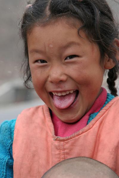 Image of Excited Tibetan girl sticking out her tongue to the photographer, 