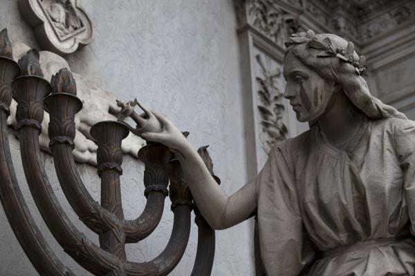 Picture of La Recoleta Cemetery (Argentina): Statue of a woman lighting a candle at a mausoleum at La Recoleta cemetery