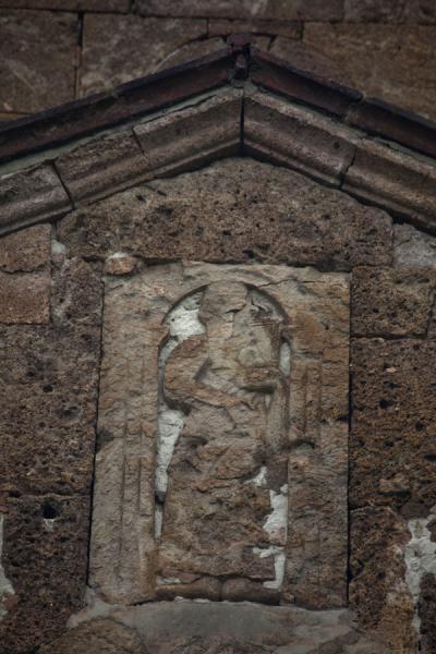 Picture of 4th century carving in the outside wall of Odzun church of figure holding a bible
