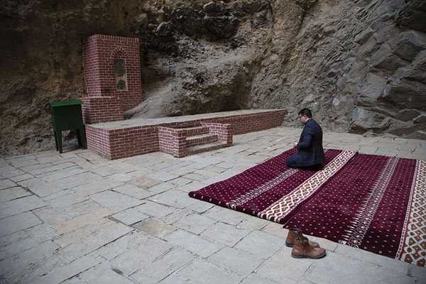 Picture of Ashabi Kahf (Azerbaijan): Man praying on a carpet in the small mosque at the higher part of Ashabi Kahf