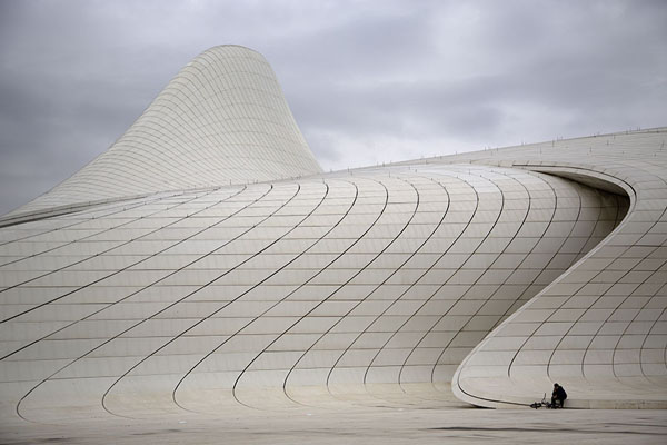 Man sitting at the foot of one of the curves of the Heydar Aliyev Centre | Heydar Aliyev Centre | Azerbaijan