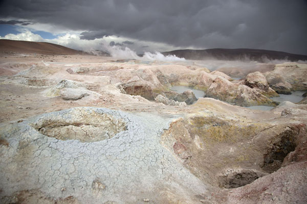 Picture of Sol de Mañana geysers (Bolivia): Dark sky over the geothermic area of Sol de Mañana with holes filled with boiling mud or emitting steam