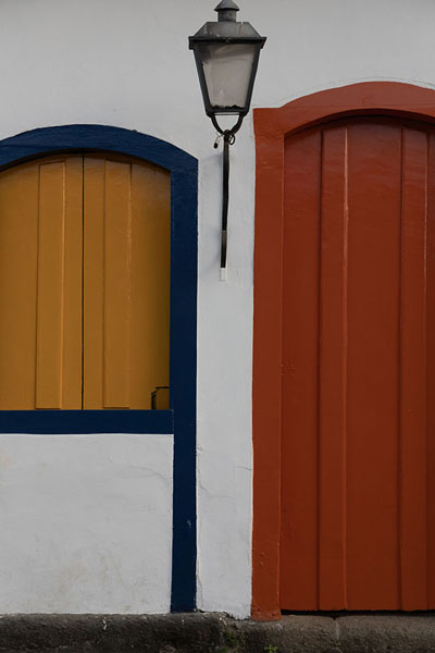 Foto van Orange and yellow painted door and window in a white house in ParatyParaty - Brazilië