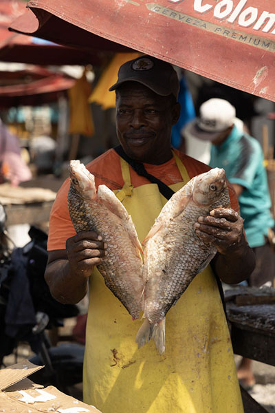 Foto van Market seller showing a fish at Bazurto marketCartagena - Colombia