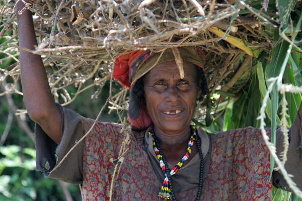 Picture of Koremi (Ethiopia): Old Koremi woman carrying firewood