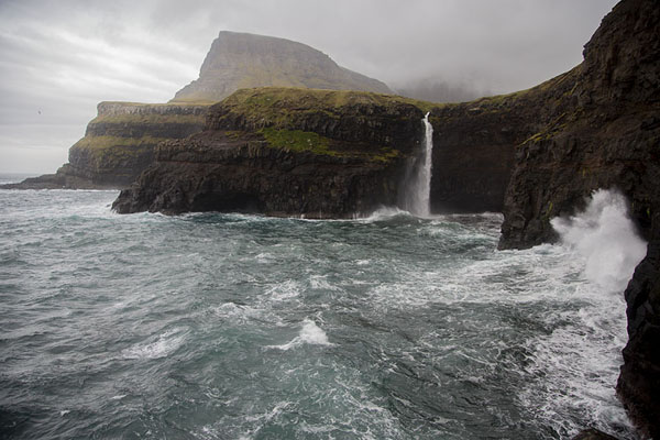 Picture of Sea level view of Múlafossur waterfall with wild waves crashing against the shore - Faroe Islands - Europe
