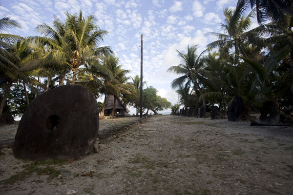 Picture of Balabat Stone Money Bank (Federated States of Micronesia): Stone money and platform with the men's house of Balabat in the background