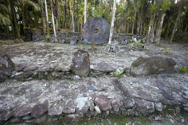 Stone platform with a few disks of stone money in the background | Banco di pietre rai | Stati Federati di Micronesia