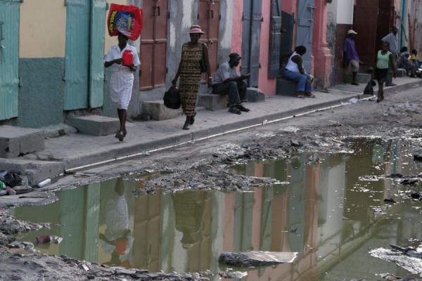 Picture of Cap Haïtien streetlife (Haiti): Reflection in a pond of people walking on the pavement in Cap Haïtien