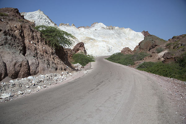Road on the west coast of Hormuz island with what looks like snow-capped mountains | Hormuz island landscapes | Iran