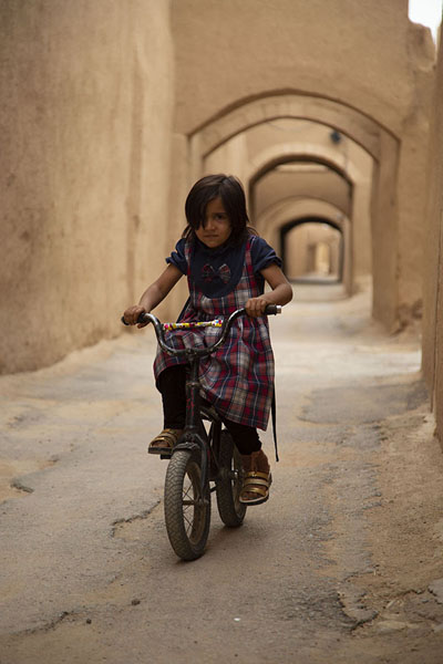 Girl cycling in an arched street of Yazd | Cité historique de Yazd | Iran