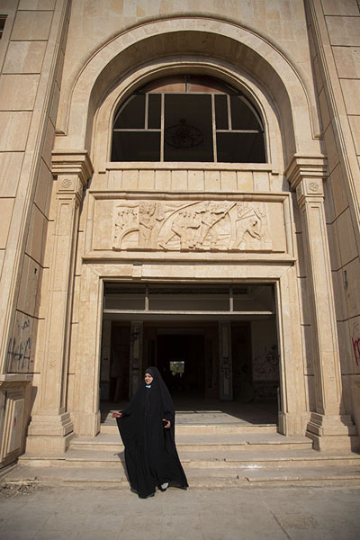 Picture of Woman walking out of the palace of Saddam with decorative element above the doorBabylon - Iraq
