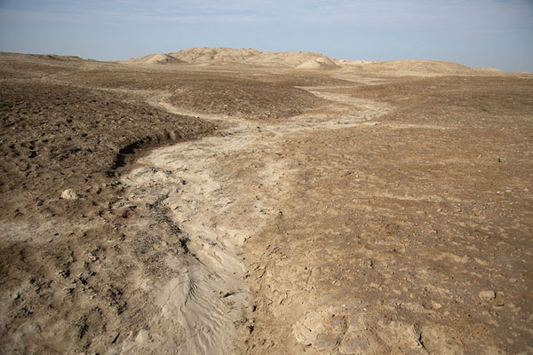 Foto van Looking across a stretch of desert towards one of the hills still hiding one of the temples of UrukUruk - Irak