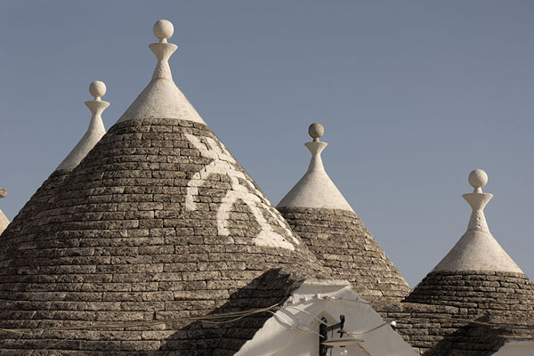 Foto van Roofs of trulli with painted signsAlberobello - Italië