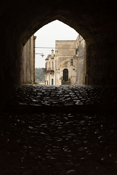 Photo de Cobblestone street under an arch in MateraMatera - l'Italie