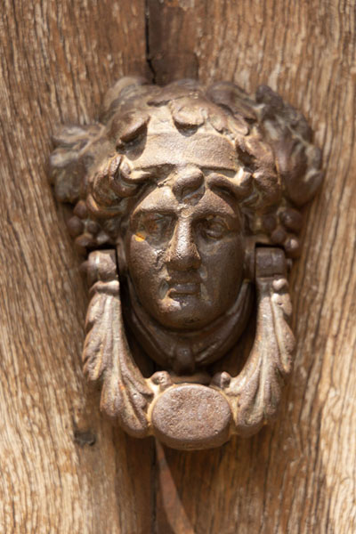 Foto van Close-up of a head sculpted on a wooden door in Rocca ImperialeRocca Imperiale - Italië
