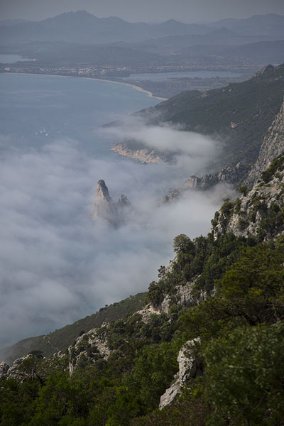 Picture of Pedra Longa enveloped by clouds seen from a high trail of Selvaggio BluSelvaggio Blu - Italy