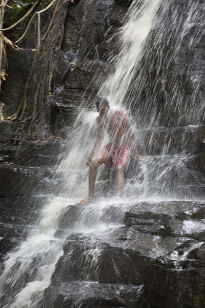 Foto di Boy enjoying a refreshing shower in the cascade - Costa d'Avorio - Africa