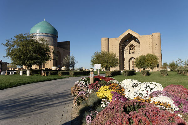Foto de Colourful flowers with the mausoleums of Rabiga Sultan Begim and Khoja Ahmed Yasawi in the background - Kazajstán - Asia