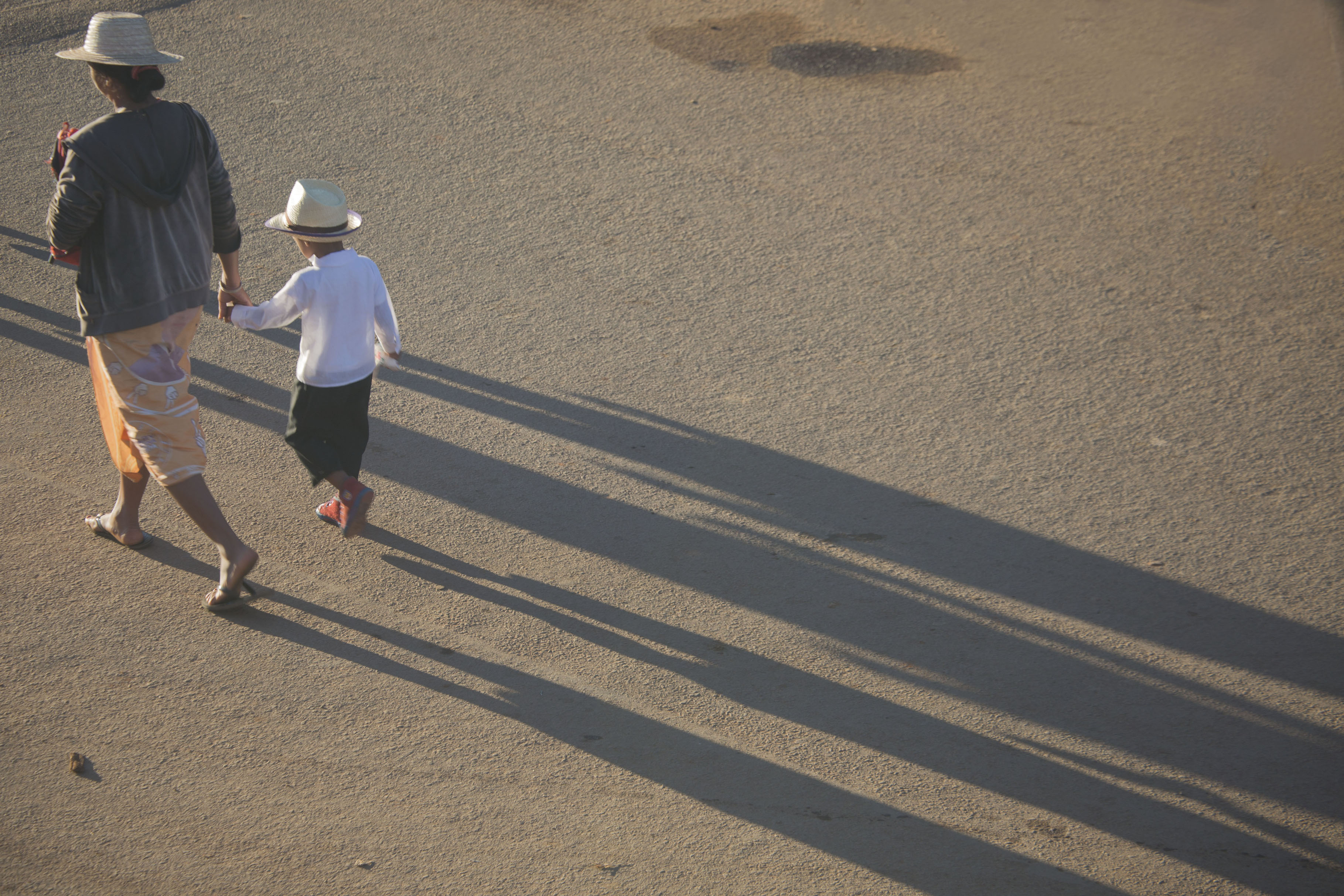 Picture of Woman and child with hat walking a street in AmbalavaoAmbalavao - Madagascar