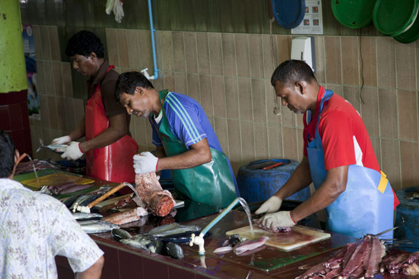 Picture of Customers waiting for men cleaning their fish at the fish market
