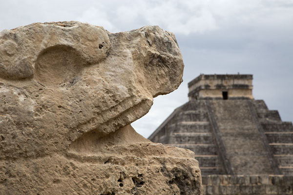 Foto de Head of a feathered serpent with Kukulcán Pyramid in the backgroundChichén Itzá - Mexico