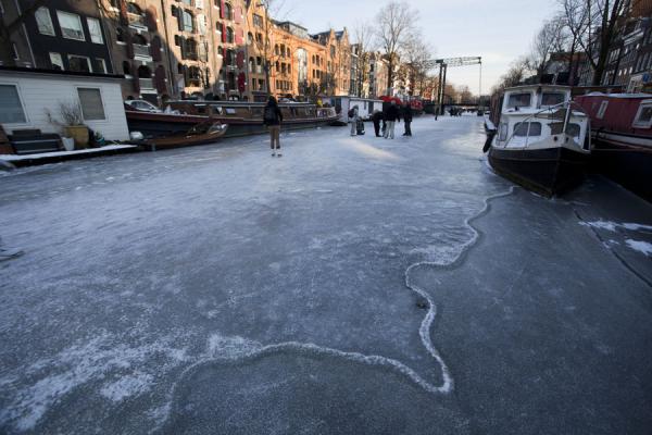 Picture of Skating Amsterdam Canals (Netherlands): Bridge and houseboats with people on a canal in Amsterdam
