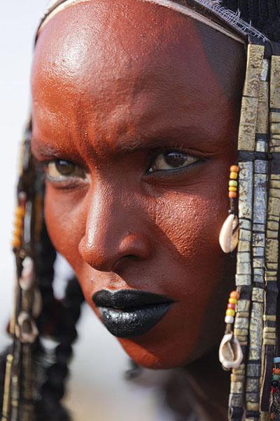 Picture of Gerewol (Niger): Young Wodaabe man with red painted face preparing for the festivities of Gerewol