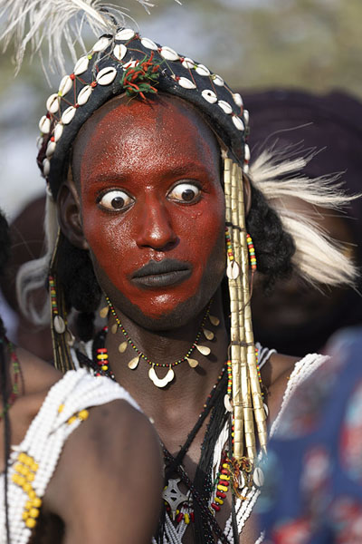 Foto di Wodaabe man making his eyes big when one of the old ladies passes byGuérewol - Niger