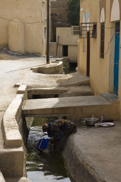 Picture of Hamra Old Town (Oman): Omani woman washing clothes in the falaj of the old town of Al Hamra