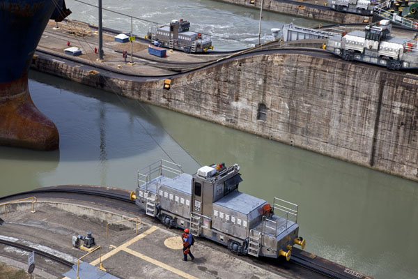 Picture of Miraflores Locks (Panama): Two silver-coloured locomotives pulling a ship through the Miraflores locks