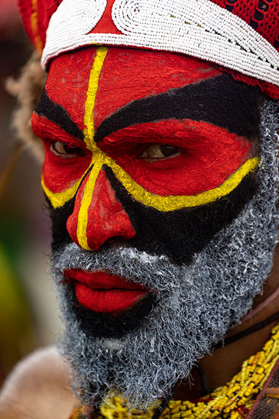 Picture of Red, yellow and black painted face of a fiercely looking man at the Mount Hagen Festival - Papua New Guinea - Oceania