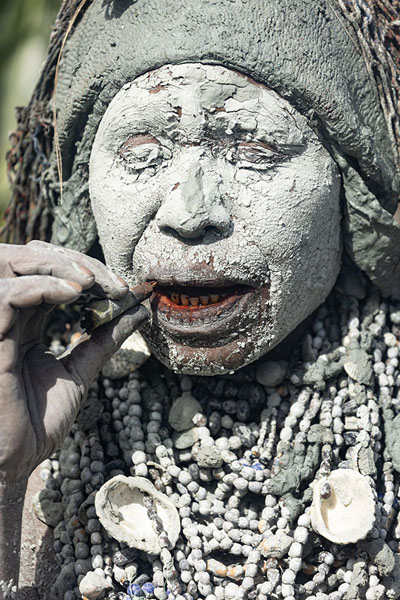 Foto van Woman covered in clay, wearing a necklace and smoking a handmade cigaretteMount Hagen - Papoea Nieuw Guinea