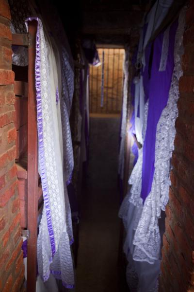 Picture of Nyamata Genocide Memorial (Rwanda): Cellar with coffins and bones behind white and purple curtains