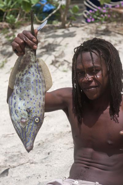 Foto van Fisherman proudly showing a flute fish before stripping its skinUnion  Island - Saint Vincent en de Grenadines