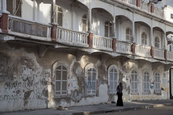 Woman walking past one of the balconied buildings in Saint Louis | Saint Louis Senegal | Senegal