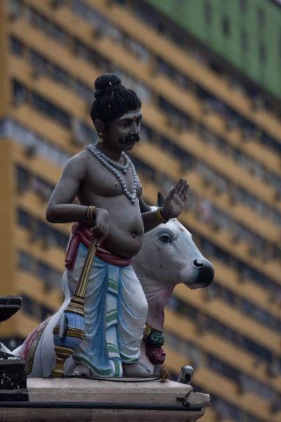 Sculpture of man with a cow in the background, and one of the modern buildings | Sri Mariamman temple | Singapore