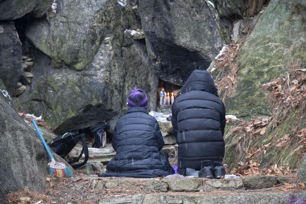 Two Koreans sitting down at a yong-wan shrine (dragon king of the waters) in prayer | Inwangsan | South Korea