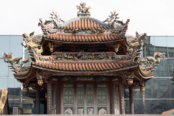 Building of the Longshan Temple with modern building ih the background | Templo de Longshan | Taiwán
