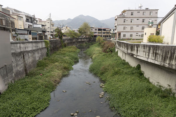 Picture of Canal with vegetation running through Meinong