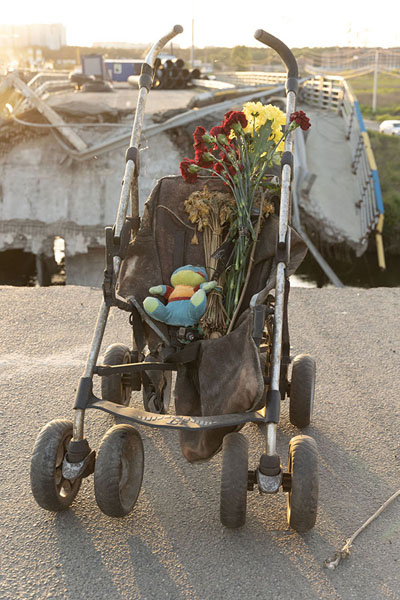 Picture of Destroyed bridge with stroller and flowers on it near Irpin