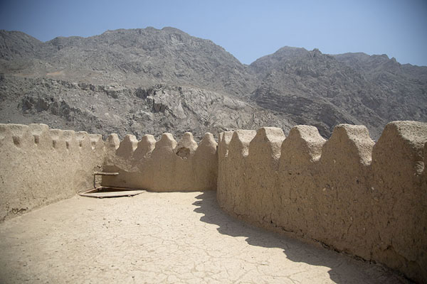 Picture of Dhayah Fort (United Arab Emirates): Crenellated wall of Dhayah Fort with mountains in the background