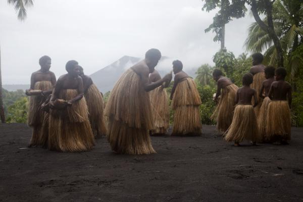 Picture of Tanna traditional village (Vanuatu): Circling the platform in traditional attire with Mount Yasur in the background
