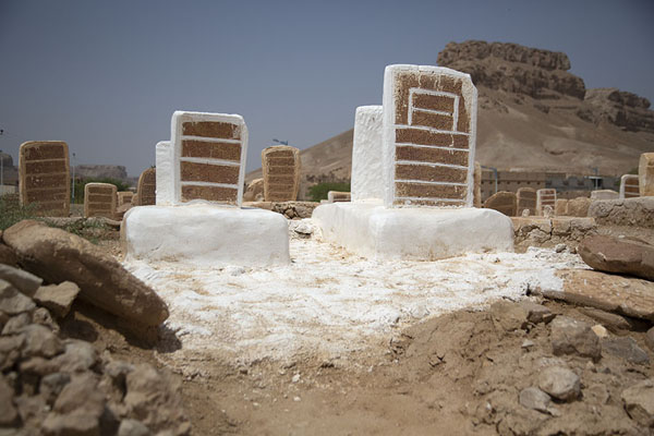 Tombstones and the cliffs of Wadi Hadramaut in the background | Aynat | Jemen