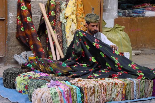 Trader in the suq organizing his wares while chewing qat | San'a suq | Yemen
