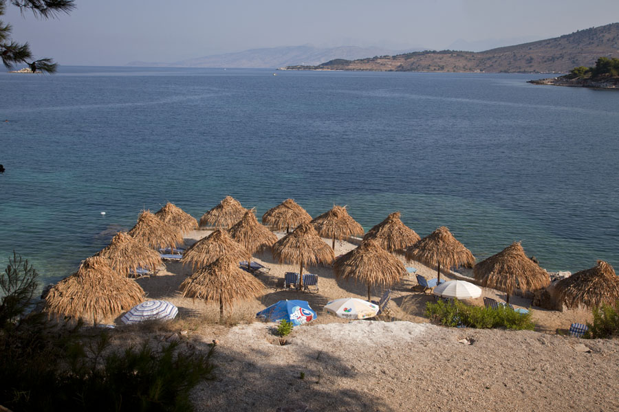 Empty beach with straw parasols in the bay of Ksamil, Albania