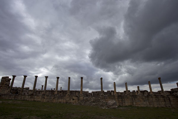 Dark clouds over the row of columns on the northern side of Severus Square | Djemila | Algeria
