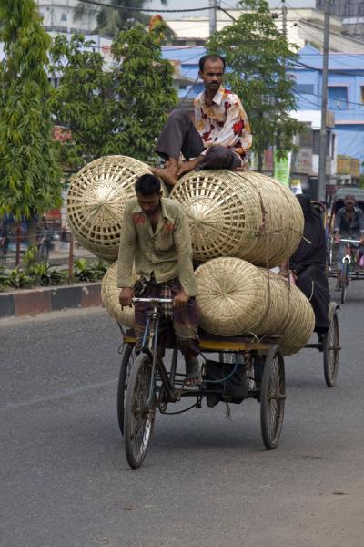Strong Bangla biker pedaling his bike with baskets and friend forward, Bangladesh Scores of baskets with someone on top - poor biker!, Bangladesh