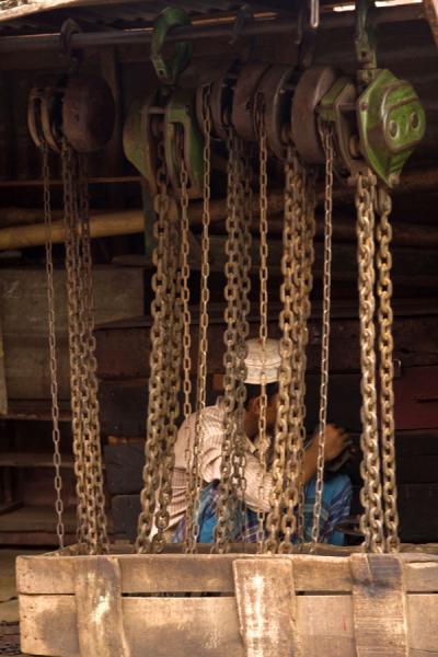 Rusty chains and man in the shipyard of Dhaka, Bangladesh