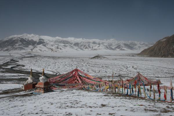 Prayer flags and snowy mountains at Batang sky burial site, China